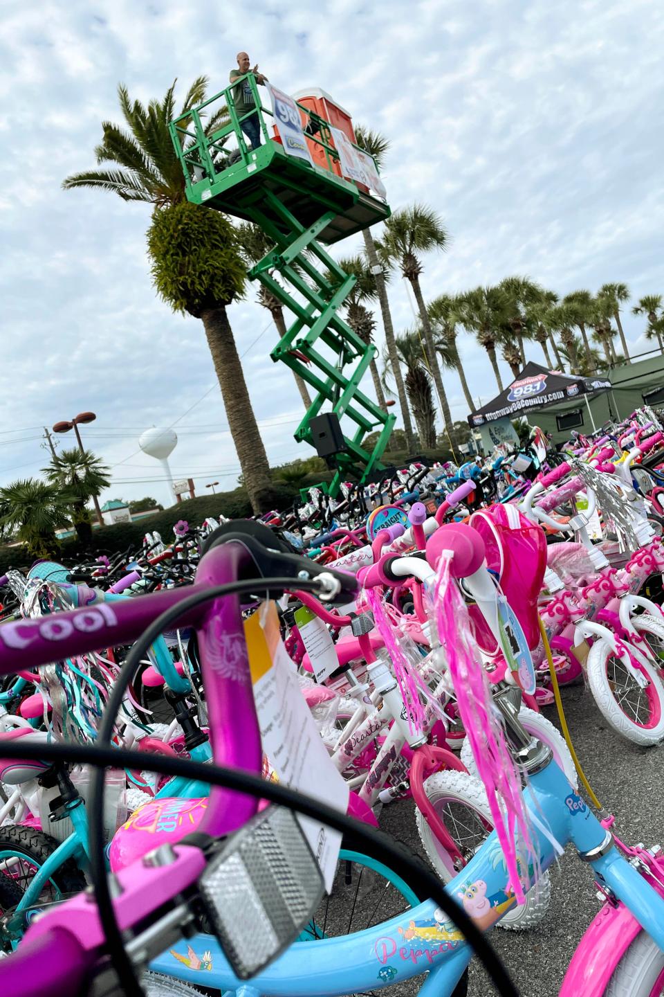 Highway 98 Country radio host Scott Mallory stands atop a scissor lift at Uptown Station in Fort Walton Beach as he surveys some 450 bicycles that were collected during Highway 98 Country's Bikes or Bust Christmas bicycle and toy drive.