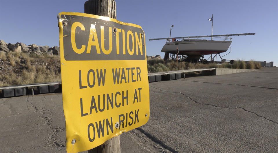 A "CAUTION LOW WATER LAUNCH AT OWN RISK" sign is displayed at the Great Salt Lake Marina on June 3, 2021, near Salt Lake City. The boats were removed this year to keep them from getting stuck in the mud. (AP Photo/Rick Bowmer)