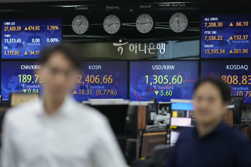 Currency traders walk near the screens showing the Korea Composite Stock Price Index (KOSPI), center left, and the foreign exchange rate between U.S. dollar and South Korean won at a foreign exchange dealing room in Seoul, South Korea, Wednesday, March 22, 2023. Asian shares advanced Wednesday after a Wall Street rally led by the banks most beaten down by the industry’s crisis.(AP Photo/Lee Jin-man)