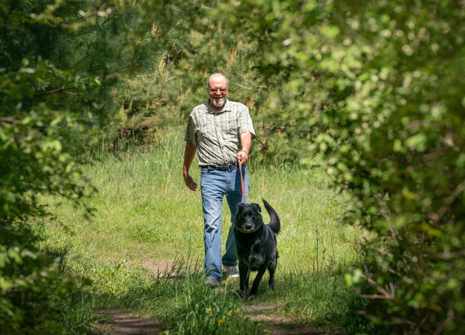 Terry McIntee, 64, of Fremont, walks his dog Winston, a 7-year-old lab mix, on Wednesday, May 8, 2024 on trails around his home.