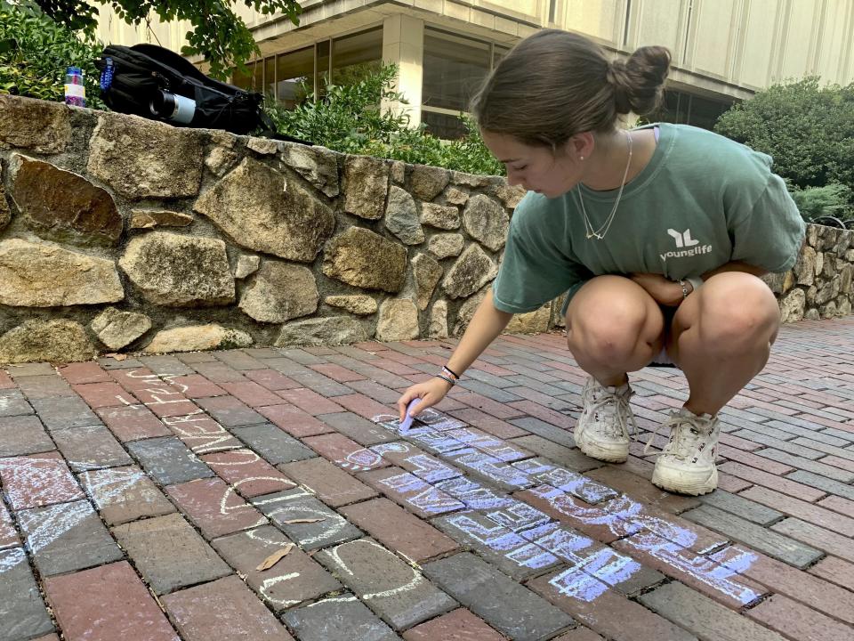 UNC-Chapel Hill sophomore Ashley Tatem writes "Heal Together" on a walking path outside the campus student center in Chapel Hill, N.C., Tuesday, Aug. 29, 2023, the day after a graduate student fatally shot his faculty adviser. (AP Photo/Hannah Schoenbaum)