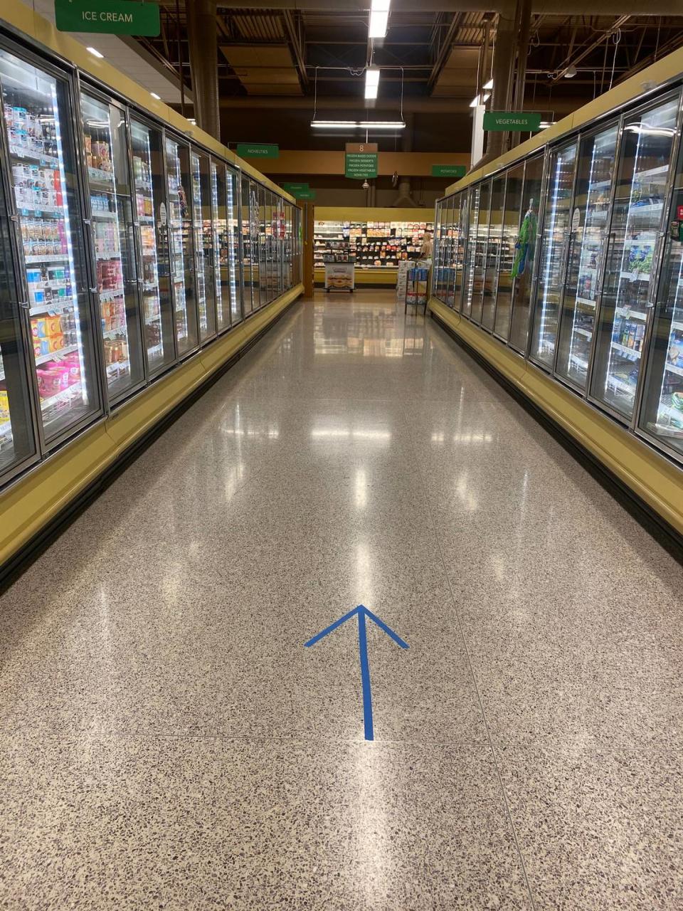 Because of the chance to spread the coronavirus, warning signs addressing social distancing hang in the aisles and directional signs on the floors ask customers to all go the same direction in Publix grocery stores around Charlotte on Wednesday, April 8, 2020.
