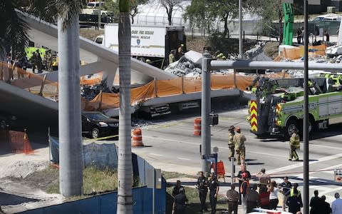 ehicles are seen trapped under the collapsed pedestrian bridge - Credit: Joe Raedle/Getty