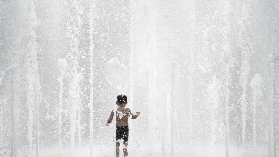 Einen Riesenspaß hat ein kleiner Junge bei sommerlichen Temperaturen im Fontänenbrunnen des Walther-von-Cronberg-Platzes in Frankfurt am Main. Foto: Arne Dedert