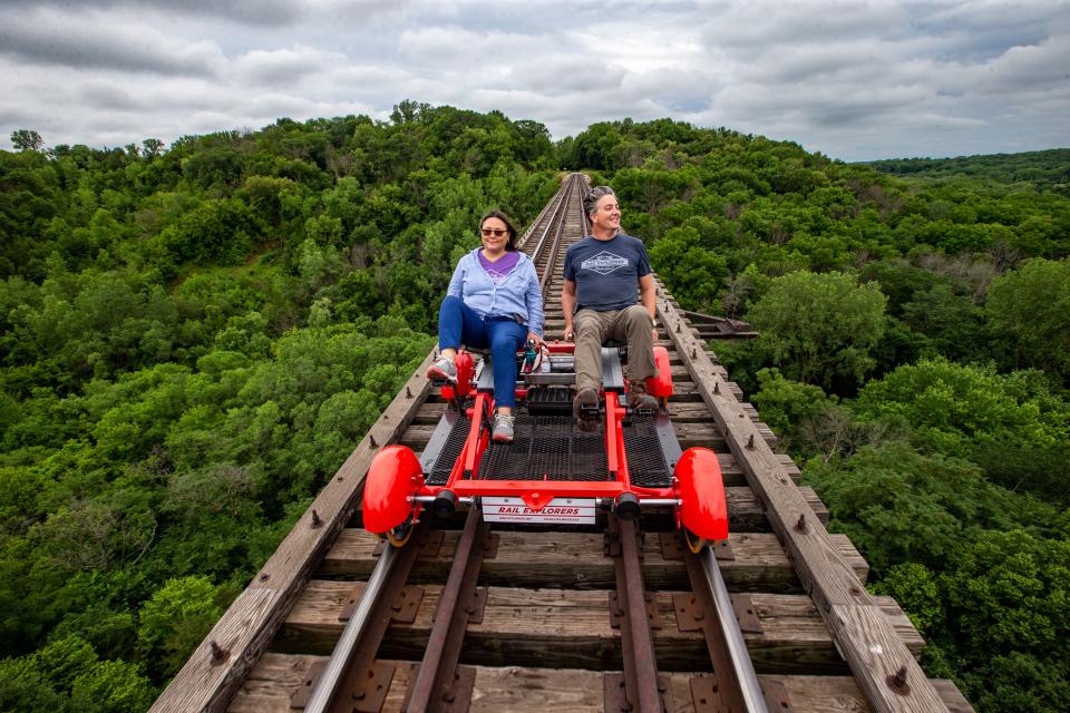 Mary Joy Lu, CEO of Rail Explorers and her husband Alex Catchpoole, Rail Explorers COO, ride over the 156-foot-tall Bass Point Creek High Bridge outside of Boone, Wednesday, July 6, 2022.