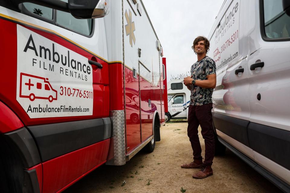 A man stands between two vehicles.