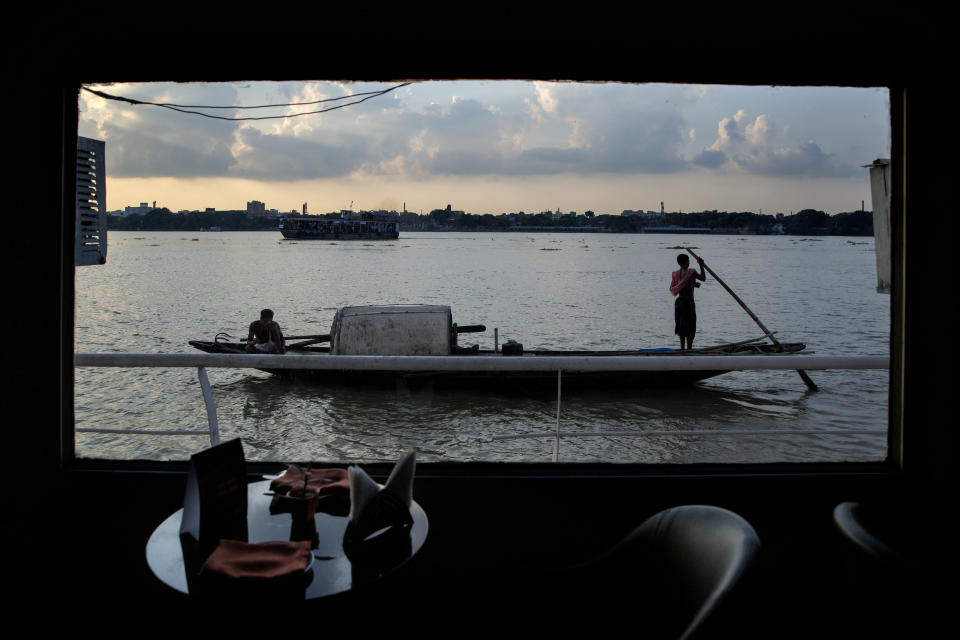 A fisherman boat moves past a floating hotel on the river Hooghly, a distributary of the river Ganges, in Kolkata, in the eastern Indian state of West Bengal, Friday, Oct. 11, 2019. Once the capital of the British raj, today the seething metropolis is home to nearly 15 million people. The Hooghly is also known as the Ganga by locals. (AP Photo/Altaf Qadri)