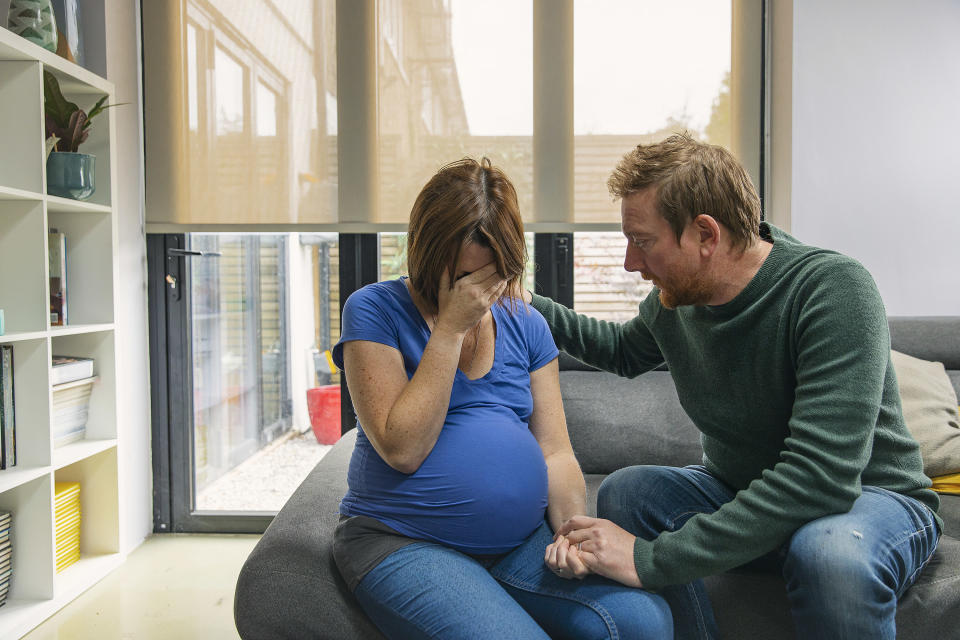 a pregnant woman and a man looking sad