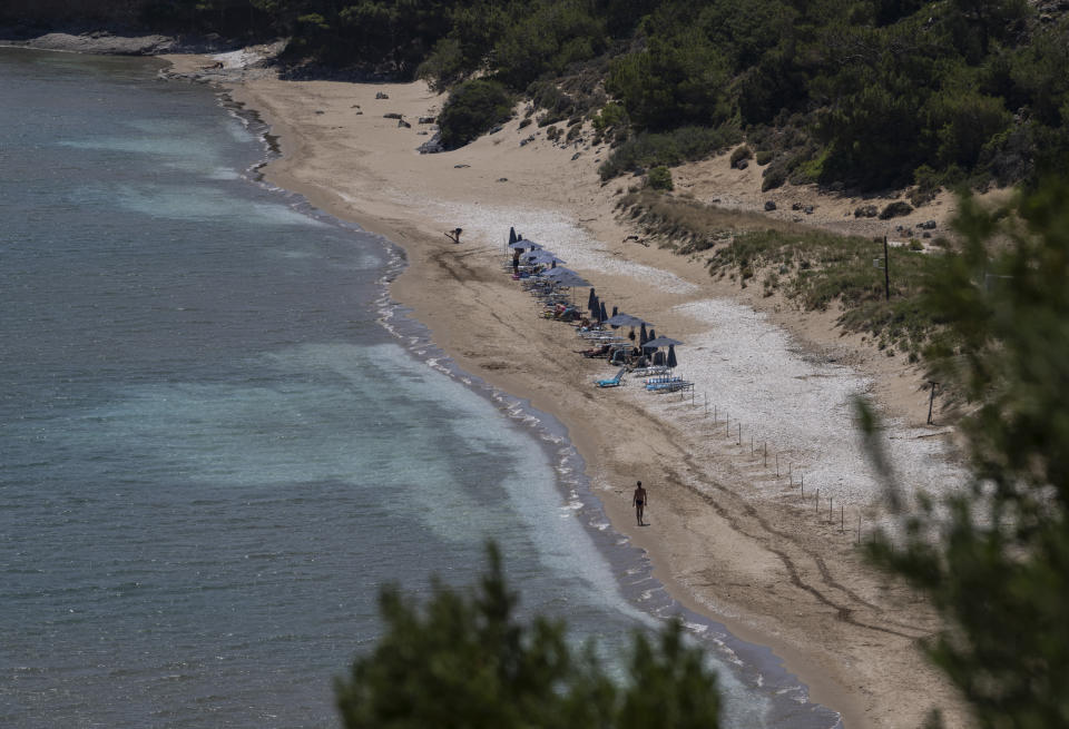 A man walks at the beach of Marathokampos, on the island of Samos, North Aegean, Greece, Wednesday June 9, 2021. An inflatable dinghy carrying nearly three dozen people reached the Greek island of Samos from the nearby Turkish coast. Within 24 hours, refugee rights groups say, the same group was seen drifting in a life raft back to Turkey. But of the 32 people determined to have initially made it to Samos, only 28 were in the raft the Turkish coast guard retrieved at sea. Days later, the missing four, a Palestinian woman and her three children, appeared in Samos' main town, apparently having eluded authorities. (AP Photo/Petros Giannakouris)