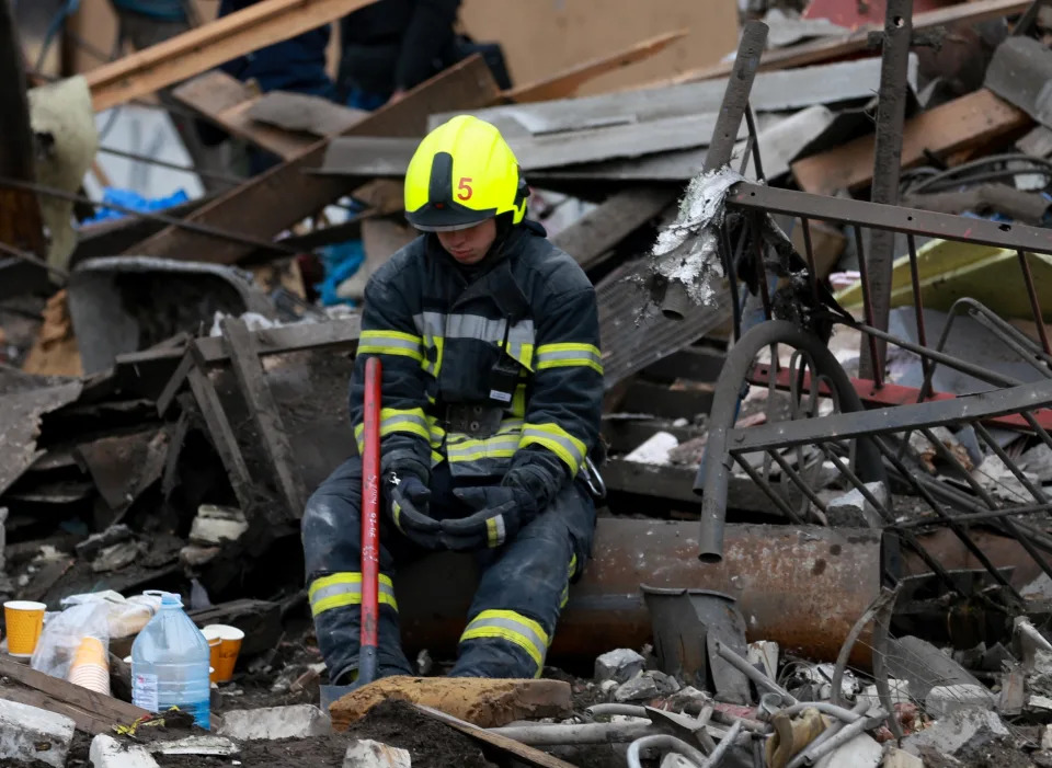 A search and rescue worker sits amid debris.