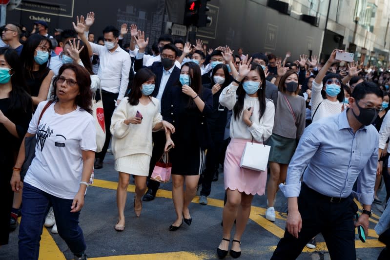 Office workers shout slogans as they attend a lunchtime anti-government protest in the Central district of Hong Kong