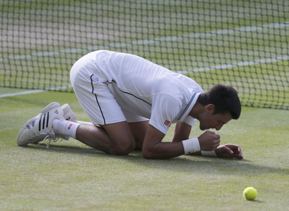 Novak Djokovic of Serbia eats some grass after defeating Roger Federer of Switzerland in their men's singles final tennis match at the Wimbledon Tennis Championships, in London July 6, 2014. REUTERS/Suzanne Plunkett