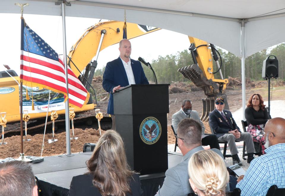 Timothy Cooke, director/CEO of the Orlando VA Healthcare System, speaks Tuesday to about 50 people at a groundbreaking ceremony for the Daytona Beach VA Multi-Specialty Clinic soon to be under construction on Williamson Boulevard in Daytona Beach. Bulldozers and front-end loaders were leveling and clearing the ground as Cooke and others spoke.