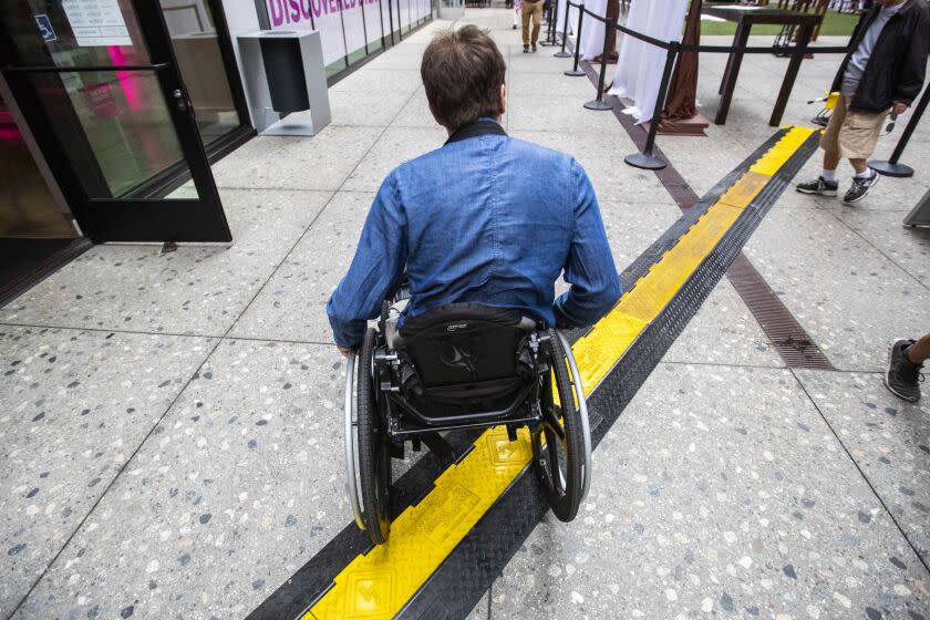 LOS ANGELES, CALIF. -- THURSDAY, SEPTEMBER 26, 2019: Television writer David Radcliff navigates his wheelchair over an electric cable channel at The Bloc shopping complex after rolling out of Metro's 7th Street Station in Los Angeles, Calif., on Sept. 26, 2019. (Brian van der Brug / Los Angeles Times)