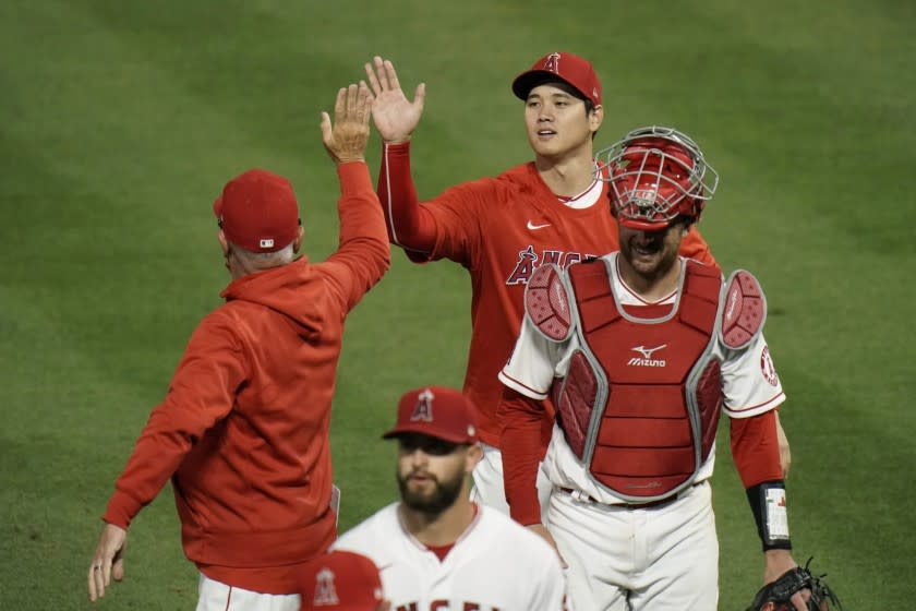 The Angels' Shohei Ohtani, top, gives manager Joe Maddon a high-five while celebrating a 9-2 win against the Dodgers.