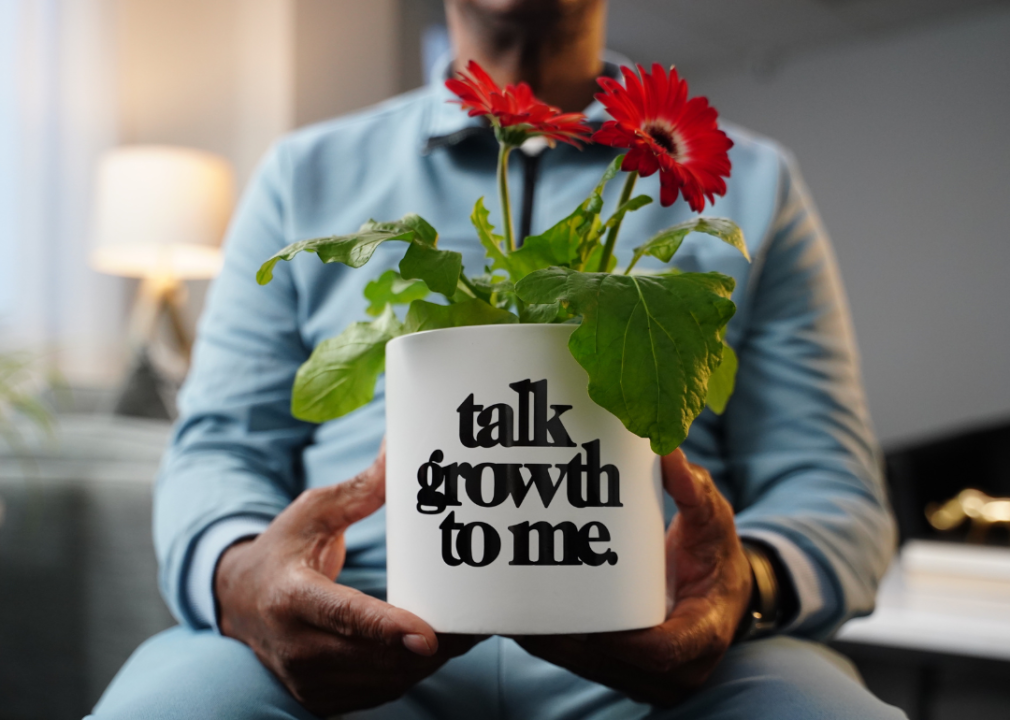 Freddie Tucker, a US veteran, holds a planter in his hands stenciled with the words "Talk growth to me."