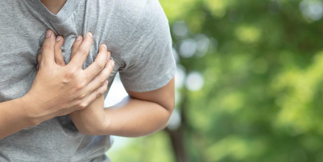 midsection of man having chest pain against trees