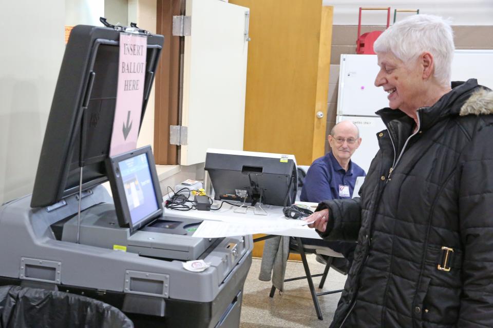 Merry Sisco, 71 of Gibsonburg, casts her ballot at Gibsonburg's precinct B, as site administrator Dan Baker looks on.