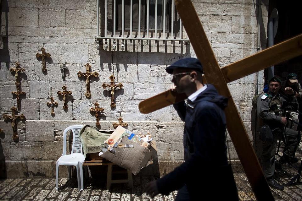 A Christian pilgrim carries a wooden crosses along the Via Dolorosa during Good Friday procession in Jerusalem, Israel.