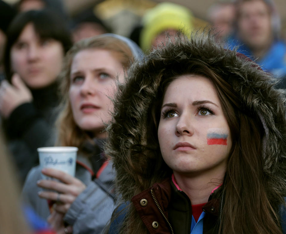 Fans watch a men's ice hockey match between USA and Russia on a large video screen at an entertainment venue associated with the 2014 Winter Olympics, Saturday, Feb. 15, 2014, in Krasnaya Polyana, Russia. (AP Photo/Charlie Riedel)