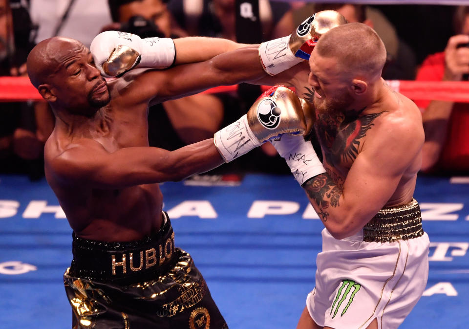 LAS VEGAS, NV - AUGUST 26:  (R-L) Conor McGregor throws a punch at Floyd Mayweather Jr. during their super welterweight boxing match on August 26, 2017 at T-Mobile Arena in Las Vegas, Nevada.  (Photo by Jeff Bottari/Zuffa LLC/Zuffa LLC via Getty Images )