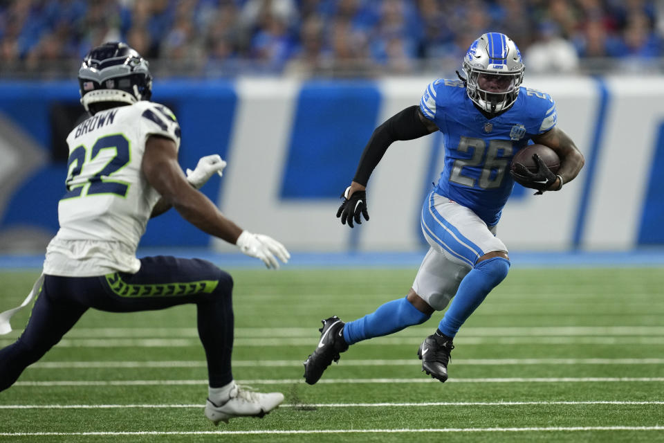Detroit Lions running back Jahmyr Gibbs (26) runs from Seattle Seahawks cornerback Tre Brown (22) during the first half of an NFL football game, Sunday, Sept. 17, 2023, in Detroit. (AP Photo/Paul Sancya)