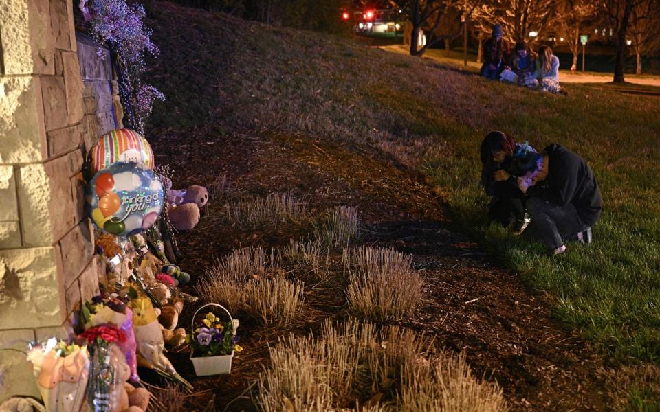 People gather at a makeshift memorial for victims outside the school - AFP