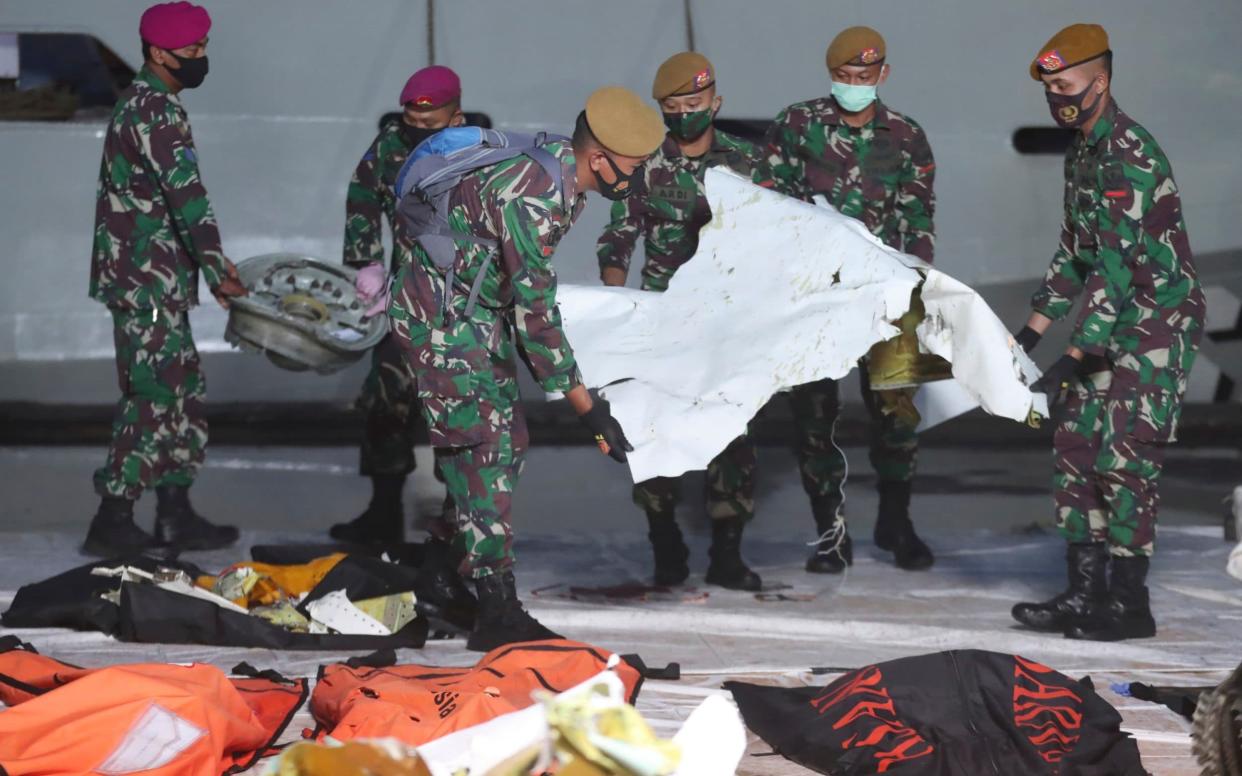 Indonesian soldiers carry pieces of the Sriwijaya Air passenger jet wreckage recovered at the search and rescue command center in Jakarta - AP