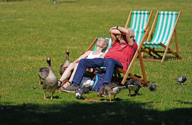 A man and a woman sunbathing on deckchairs in St James’s Park