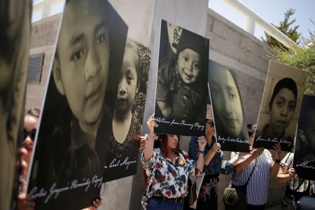 Activists hold photos of migrant children that die in U.S. custody as they protest at the Paso del Norte international border bridge, as seen from Ciudad Juarez