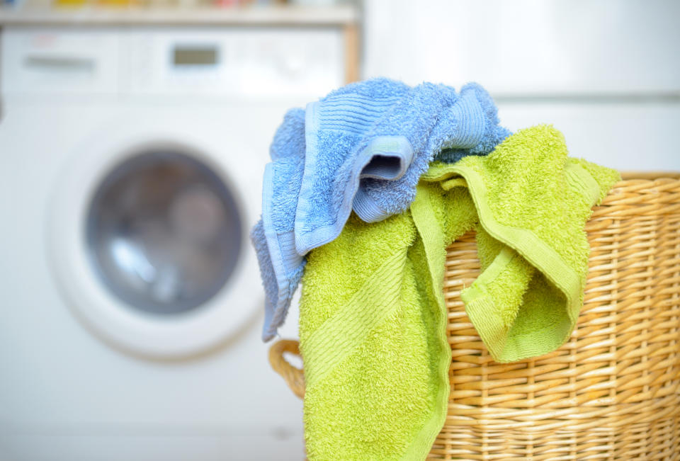 Dirty clothes basket with towels waiting for laundry with washing machine in backround