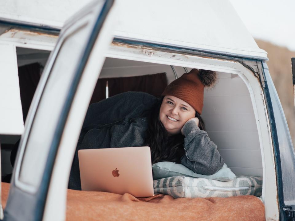 The writer lounges in the back of the van with an open MacBook in front of her