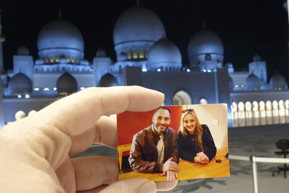 In this Aug. 19, 2019, photo provided by Aya Al-Umari, a photo of Al Noor mosque shooting victim, Hussein Al-Umari and his sister Aya is held by her at the Sheikh Zayed Grand Mosque in Abu Dhabi, United Arab Emirates. New Zealanders on Sunday, March 15, 2020, will commemorate those who died on the first anniversary of the mass killing, as the tragedy continues to ripple through the community. Three people whose lives were forever altered that day say it has prompted changes in their career aspirations, living situations and in the way that others perceive them. (Aya Al-Umari via AP)