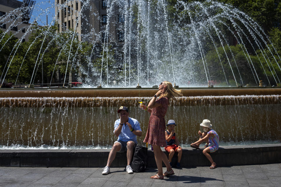 A family apply sunscreen to protect themselves from the sun on a hot and sunny day in Barcelona, Spain, Friday, July 15, 2022. (AP Photo/Emilio Morenatti)