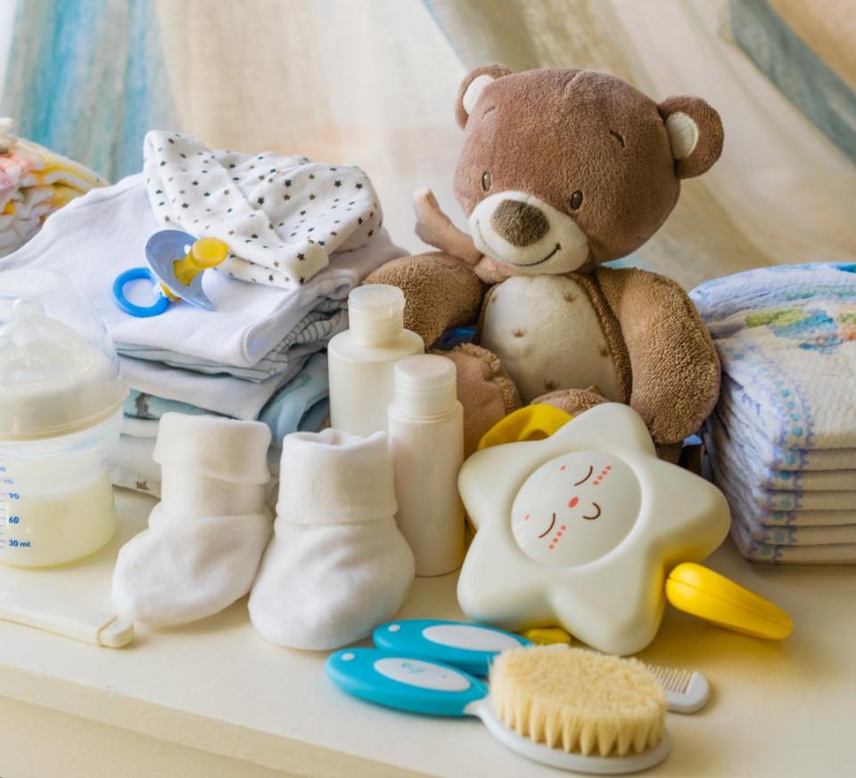 Brown teddy bear, pacifier, star shaped toy, baby shoes and baby bottle on top of a white dresser