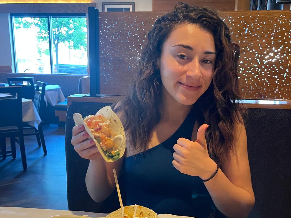 The writer holds a shrimp taco at Bonefish Grill and gives a thumbs up