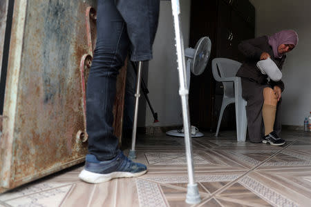 Palestinian woman Nazeeha Qudieh, 38, who, according to medics, lost her right leg after she was shot by Israeli forces during a protest at the Israel-Gaza border, puts on her artificial limb as her brother Suhaib, 33, who also lost a leg in the protests, stands at their house in Khan Younis in the southern Gaza Strip April 1, 2019. REUTERS/Mohammed Salem/Files