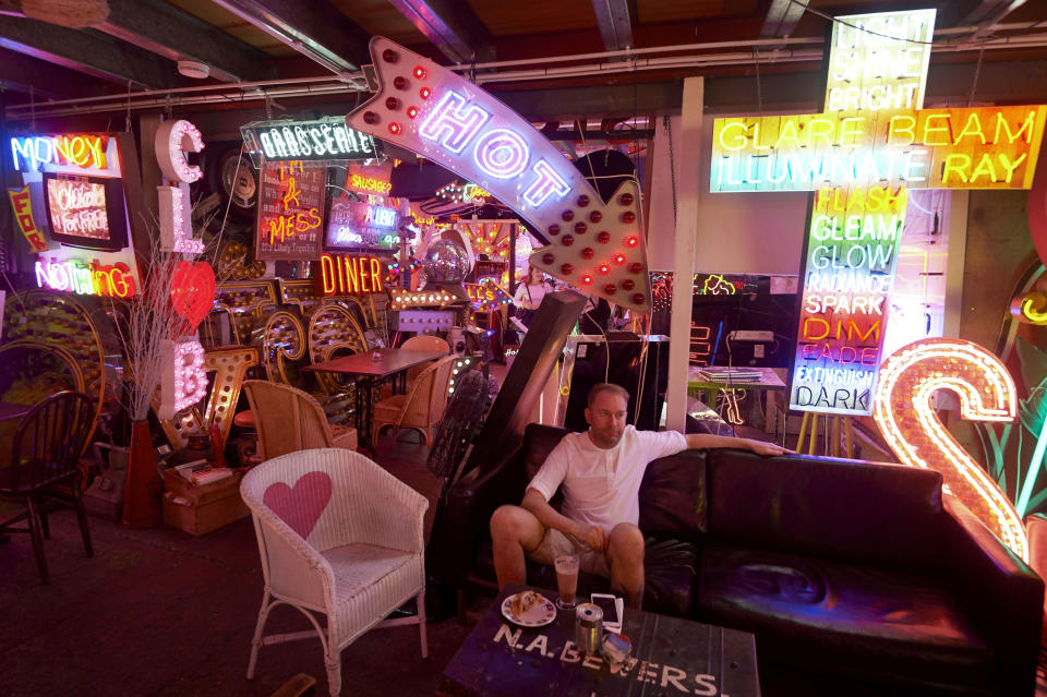 A patron relaxes amidst an array of neon lights and signs is displayed inside God's Own Junkyard gallery, cafe and workshop in Walthamstow, east London on July 8, 2017. 
Whether in search of a glowing skull or bright red heart, God's Own Junkyard in London offers a labyrinth of neon which is thriving on its retro reputation.  / AFP PHOTO / NIKLAS HALLE'N / TO GO WITH AFP STORY by Edouard GUIHAIRE        (Photo credit should read NIKLAS HALLE'N/AFP via Getty Images)