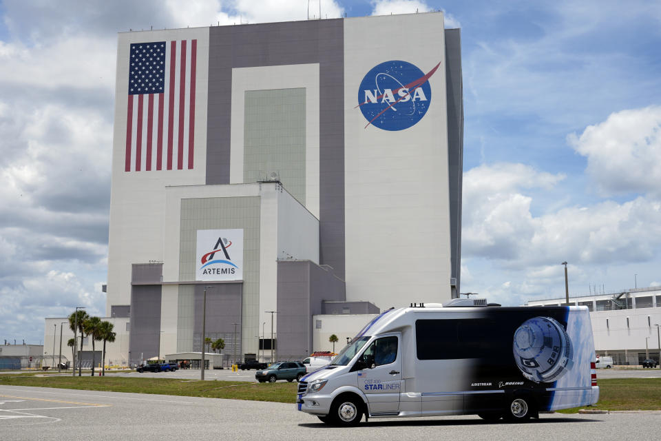 NASA astronauts Butch Wilmore and Suni Williams, riding in the astro van, drive by the Vehicle Assembly Building on the way back to the operations and checkout building after the launch was scrubbed Saturday, June 1, 2024, in Cape Canaveral, Fla. (AP Photo/Chris O'Meara)