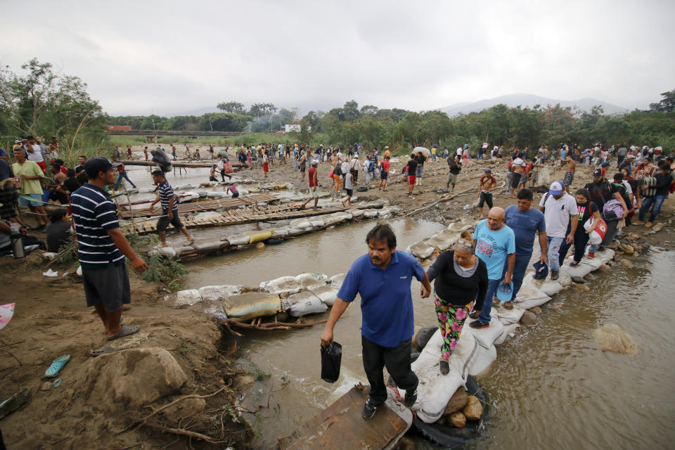 People cross the Tachira River into Colombia near the Simon Bolivar International bridge, which Venezuelan authorities only open to students and the sick, in Cucuta, Colombia, Tuesday, March 12, 2019, on the border with Venezuela. People crossing the river are using makeshift bridges as the water level grows with the approaching rainy season. (AP Photo/Schneyder Mendoza)