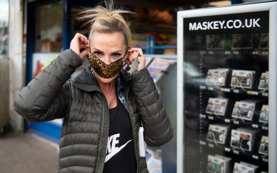 Chigwell resident Laura Gilbert 55 buys a mask from a face mask vending machine on Chigwell High Road - GEOFF PUGH
