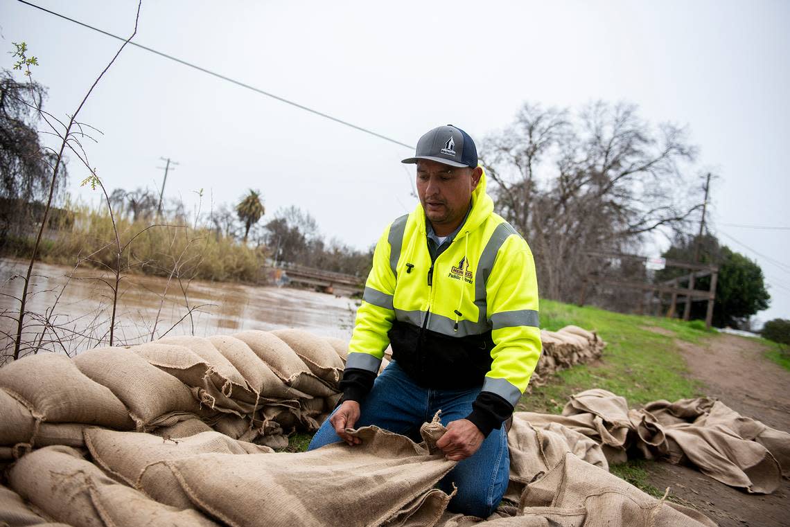 City of Merced Public Works employee Jesus Montes, 42, works to construct a sandbag wall with co-workers along Bear Creek near the intersection of W Street and West 23rd Street in Merced, Calif., on Wednesday, Jan. 11, 2023.