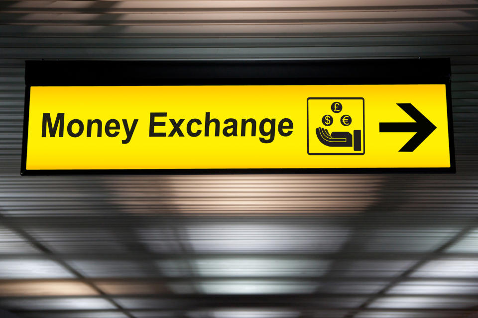 yellow money exchange direction sign hanging from the ceiling at the airport