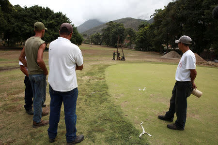 Caraballeda Golf & Yacht Club workers look at construction workers working in a new infrastructure at an expropriated golf field of the club in Caraballeda, Venezuela February 20, 2018. Picture taken February 20, 2018. REUTERS/Adriana Loureiro