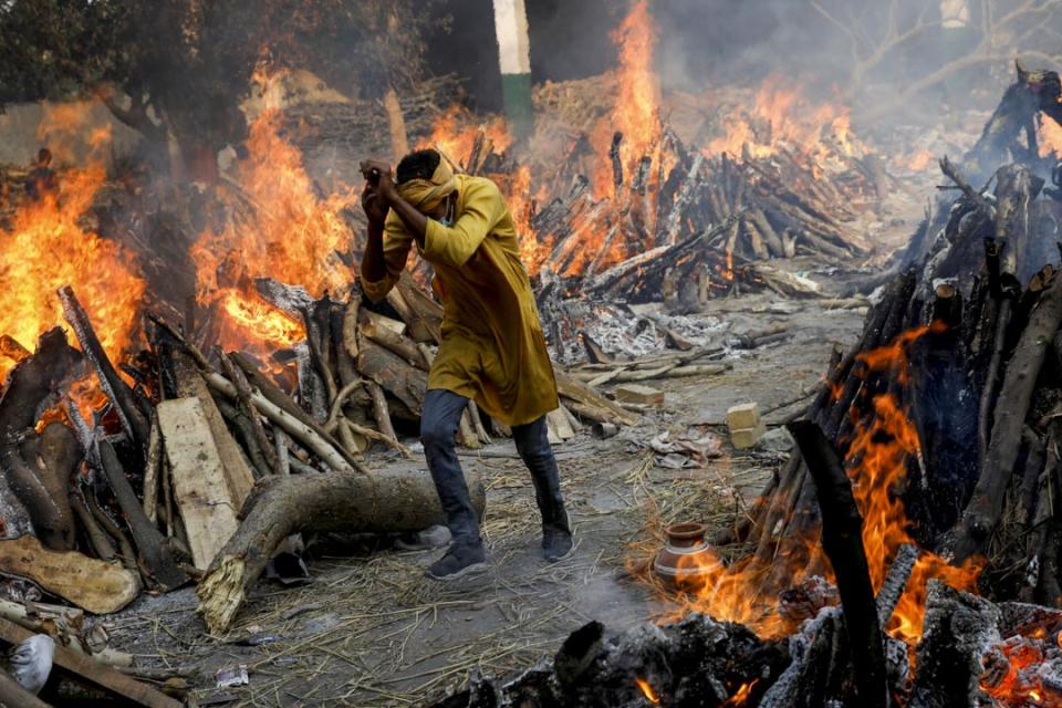 2021年4月26日，印度新德里的一個火葬場，一名男子穿過燃燒中的火堆。