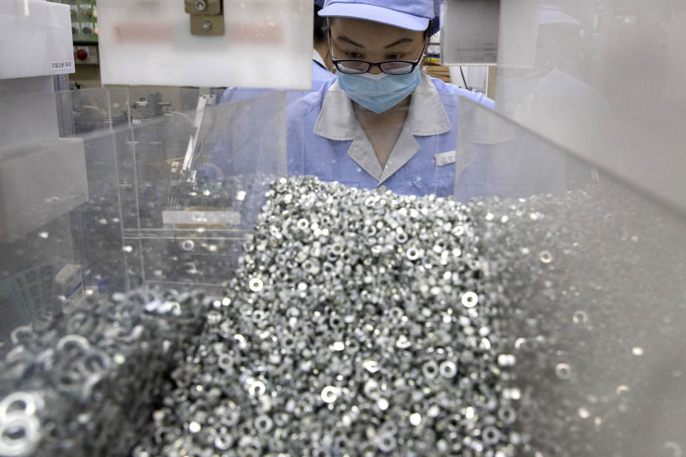In this Wednesday, May 13, 2020 photo, a worker at SMC China, a Japanese joint venture pneumatic engineering company, assembles products at a factory in Beijing. The United States, Japan and France are prodding their companies to rely less on China to make the world’s smartphones, drugs and other products. But even after the coronavirus derailed global trade, few are willing to give up access to its skilled workers, vast market and efficient suppliers by moving factories closer to home.(AP Photo/Ng Han Guan)
