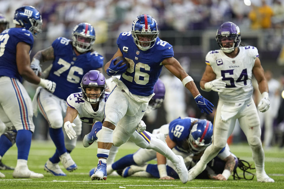 New York Giants running back Saquon Barkley (26) runs from Minnesota Vikings safety Camryn Bynum (24) during a 27-yard touchdown run in the second half of an NFL football game, Saturday, Dec. 24, 2022, in Minneapolis. The Vikings won 27-24. (AP Photo/Abbie Parr)