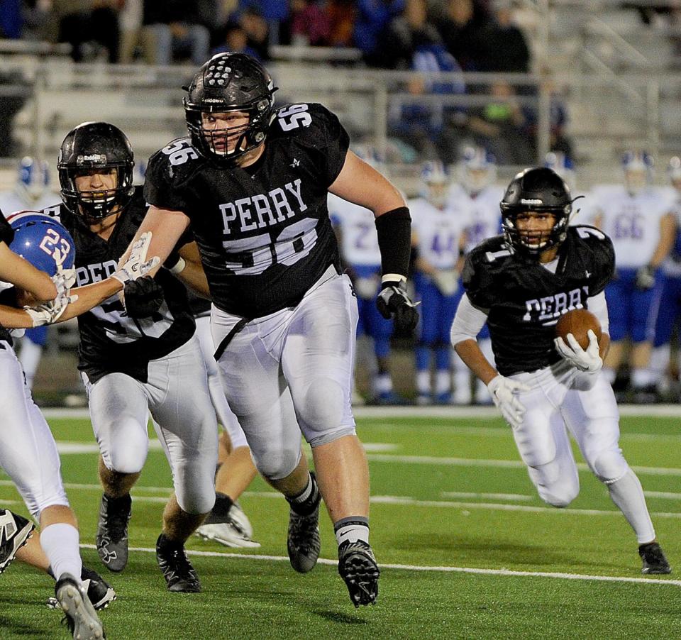 Perry's Matt Carrick (56) leads Tevion Cleveland on a 16-yard run against Lake in 2016.