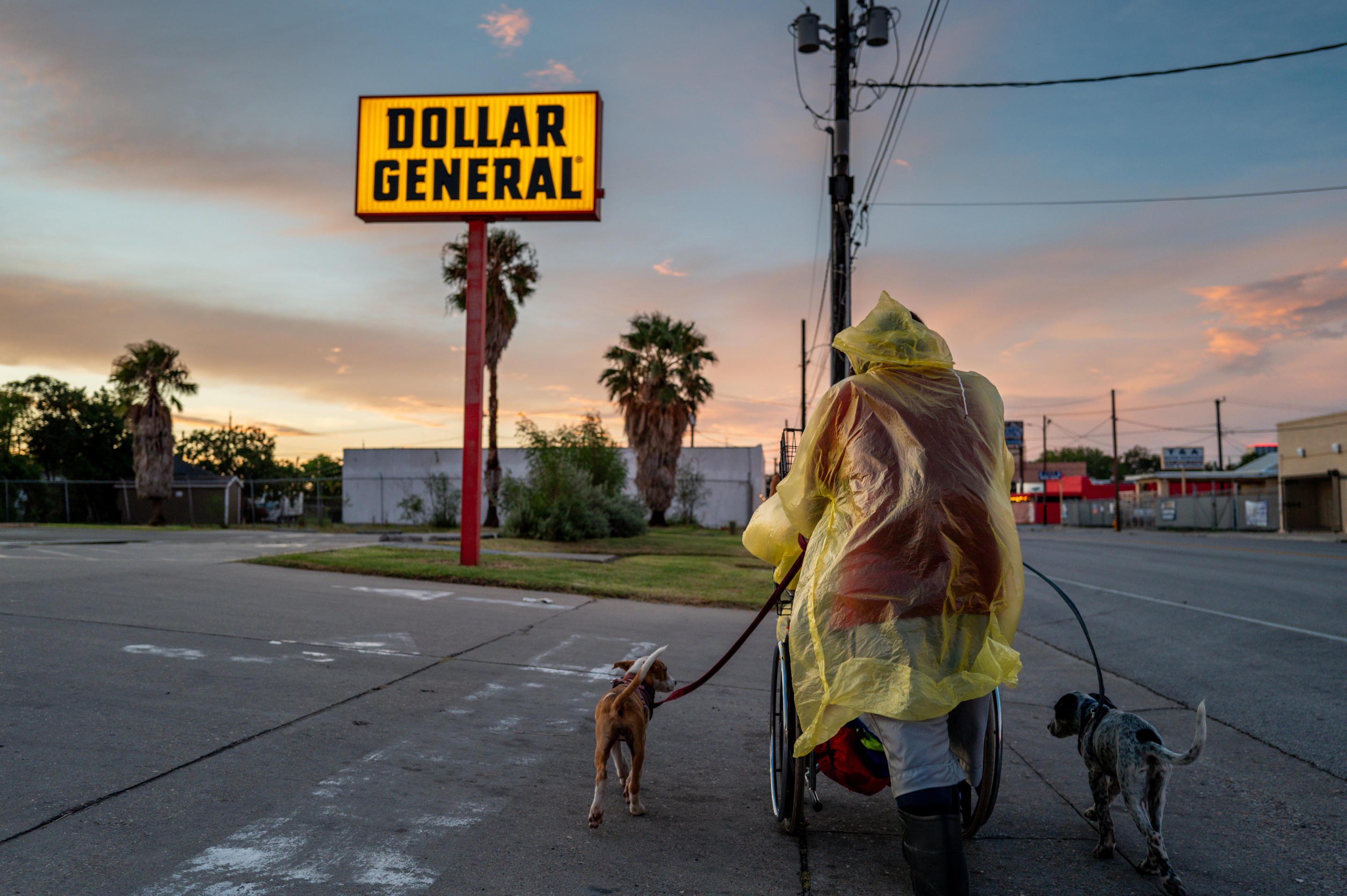 Una pareja sin hogar con dos perros se refugia cerca de una tienda Dollar General antes de la llegada de la tormenta tropical Peligro el 7 de julio en Corpus Christi, Texas.