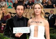 <p>‘The Big Bang Theory’ star Simon Helberg and his wife Jocelyn Towne chose to make a political display on the red carpet. Towne boldly had “let them in” written on her chest, while Helberg held up a sign stating “refugees welcome”. [Photo: Getty] </p>